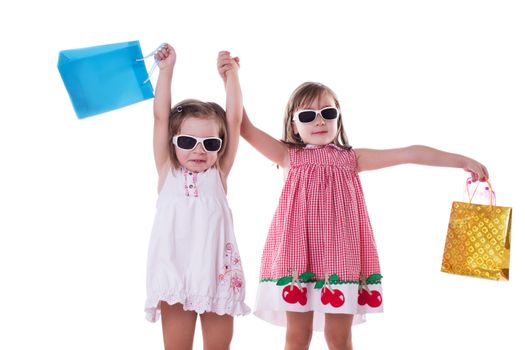 Two happy little girls in sun-glasses and shopping bags isolated on white