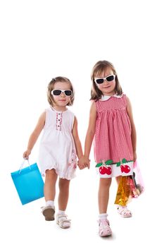Two little girls in sun-glasses and shopping bags isolated on white