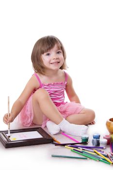 Smiling three year girl drawing with paint over white