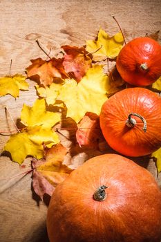 Autumn background with colored leaves and pumpkin on wooden board. Pumpkins on grunge wooden backdrop, background table. Autumn, halloween, pumpkin