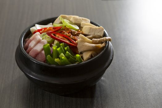 A heated stone bowl dish of korean food with pork and mushroom