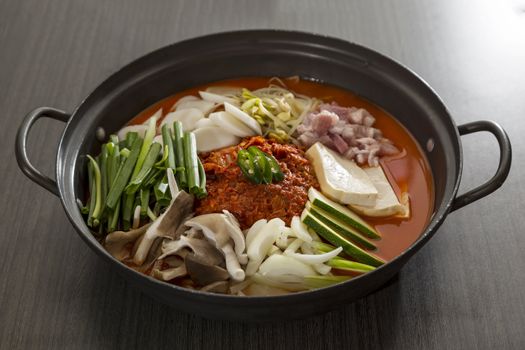 A heated stone wok of korean food with pork and mushroom