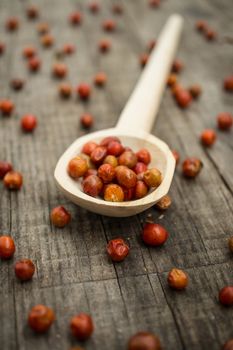 A spoon full of Chile Chiltepin on wood background