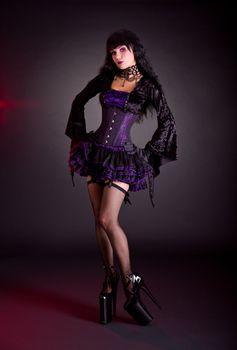 Sexy young woman in Victorian purple and black Halloween outfit and extra high heels  