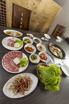 A vertical dynamic shot of korean casseroles with side dishes.