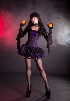 Beautiful witch in purple and black gothic fantasy Halloween costume with Jack lantern oranges 