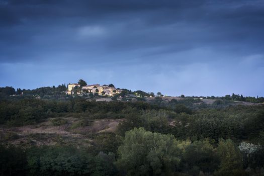 Small illuminated village on a hill in Tuscany after sunset