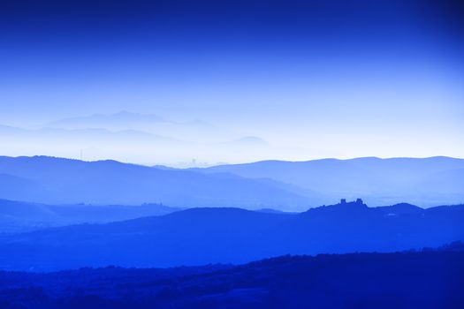 Landscape of Tuscany with hills, cypresses and houses at blue hour