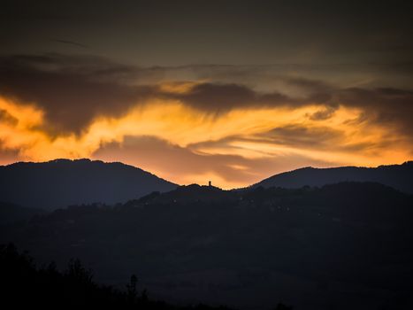 Landscape of Tuscany with hills, cypresses and golden clouds