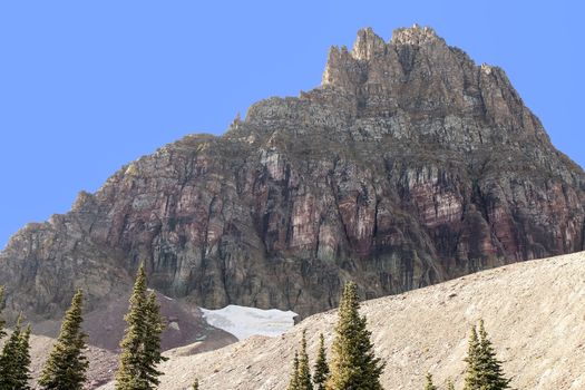 This image of Mount Reynolds at Glacier National Park shows purple rock face and remnants of a snow field.