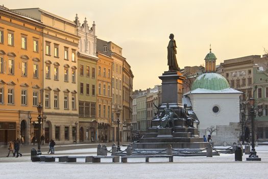 Winter sun on the buildings in the Market Square ( Rynek Glowny) with St Adalbert's Church and the Statue of Adam Mickiewicz, looking south towards Grodzka in the city of Krakow in Poland.