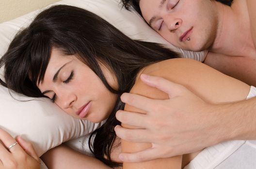 Couple in their 20s relaxed and sleeping in an embrace