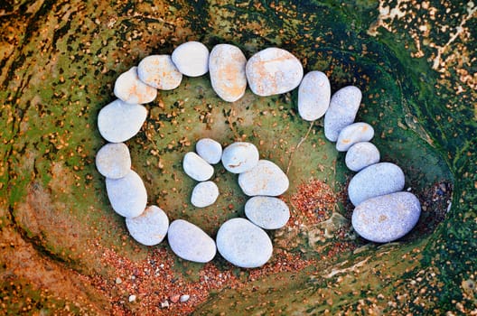 Spiral of pebbles on the sea boulder