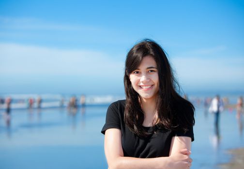Beautiful biracial young woman or teen enjoying walk along beach by Pacific Ocean