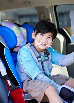 Handsome disabled six year old boy smiling in carseat