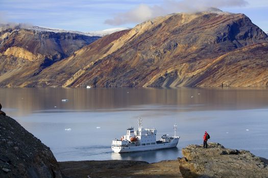 Adventure tourist and Russian Icebreaker at Blomsterbugten (Flower Bay) Franz Joseph Fjord in Eastern Greenland (Model Released)