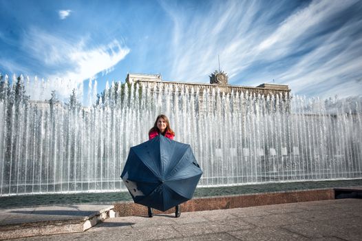 happy woman hiding behind an umbrella at the fountain