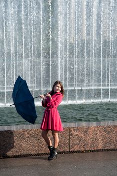 happy young woman in a red raincoat with an umbrella