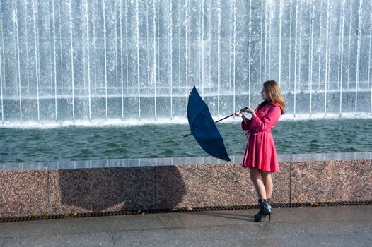 happy young woman in a red raincoat with an umbrella