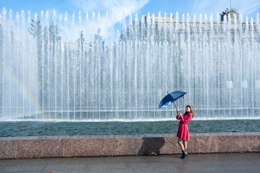 happy young woman in a red raincoat with an umbrella