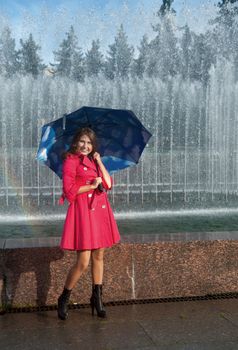 happy young woman in a red raincoat with an umbrella