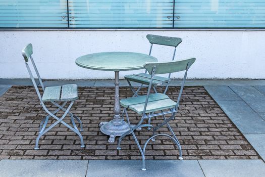 Outdoor cafe. Empty table and three chairs.