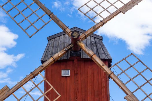 Red wooden windmill on blue sky background. Sweden.