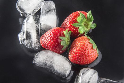 Three fresh strawberries and ice cubes