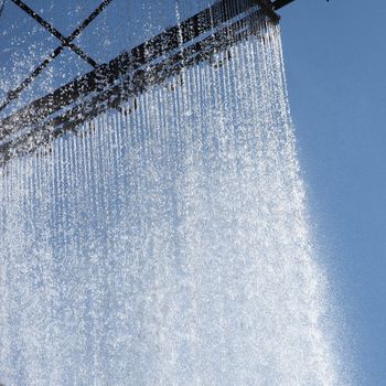 Ornamental curtain of running water on the outside of a corporate building with water droplets glistening in the son