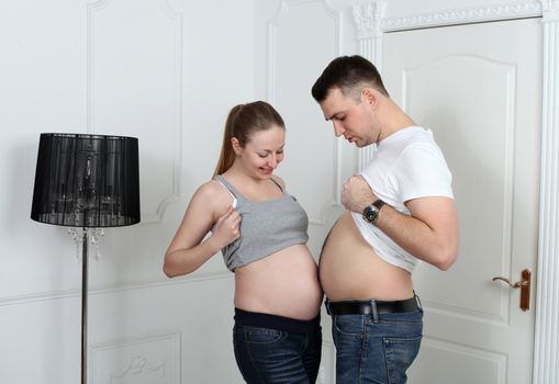 Man and pregnant woman is showing their bellies