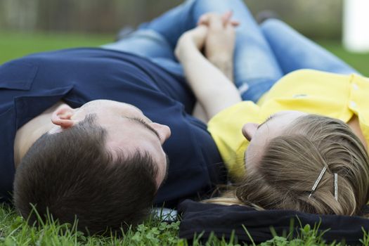 Top view of couple lying on the grass with heads together