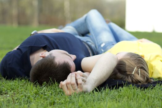 Top view of couple lying on the grass with heads together