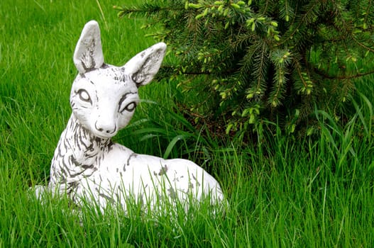 Stone white deer sculpture lying on the green lawn, Sergiev Posad, Moscow region, Russia