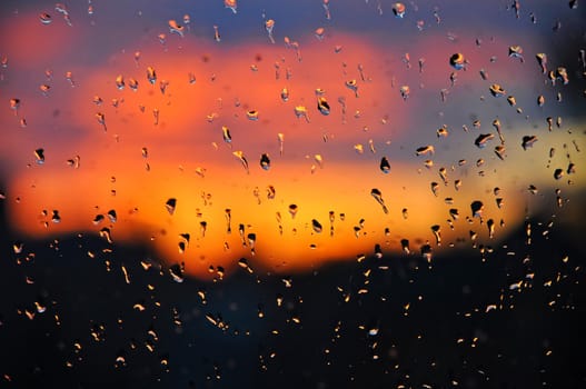 Cristal water drops on the window glass with a beautiful sunset as a background