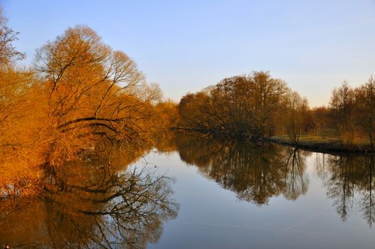 The lake with red trees without leaves in spring in Aue Park in Fulda, Hessen, Germany