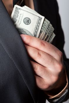 Close up of a business mans hand hiding money in his suit jacket pocket.