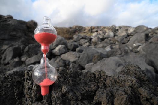 Time Concept - Hourglass Abandoned on the Volcanic Rocks