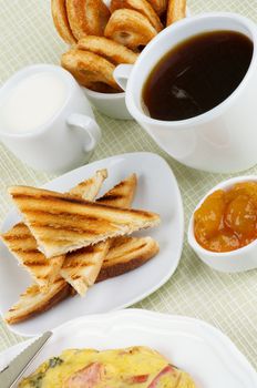 Delicious Hearty Breakfast with Toasts, Apricot Jam, Coffee, Milk and Puff Pastry closeup on light green Checkered background