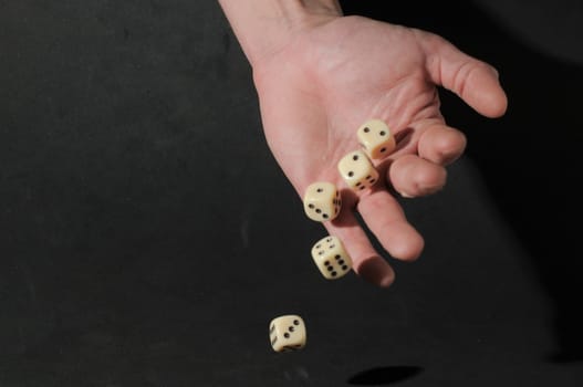 One Left Male Hand Playing Dice on a Black Background