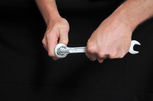 An Hand Holding a Wrench over a Black Background
