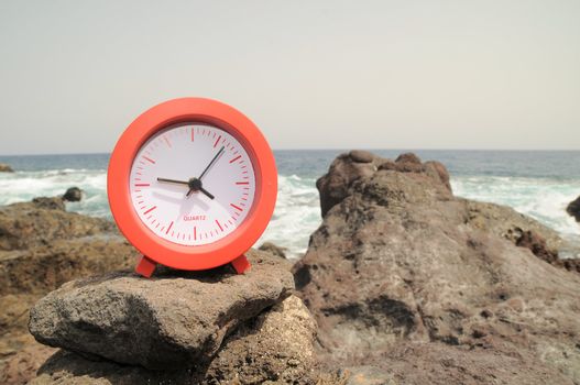 One Red Clock on the Rocks Near the Ocean 