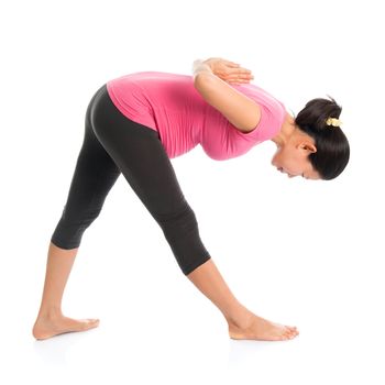 Prenatal yoga class. Full length healthy Asian pregnant woman doing yoga exercise stretching, full body isolated on white background. Yoga positions standing forward bend.