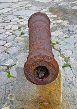 Old rusty cannon on stone background, vertical view