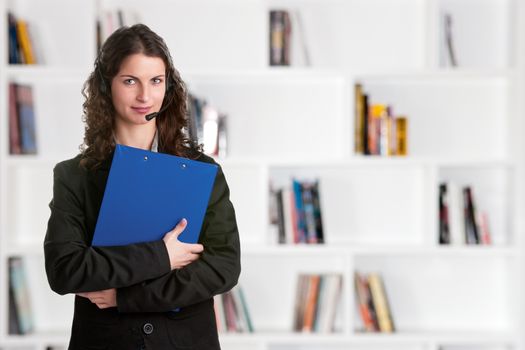 Corporate woman talking over her headset, holding a blue pad