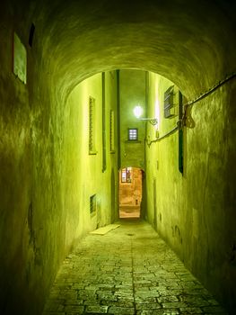 Picture of a narrow illuminated alley in Volterra, Italy