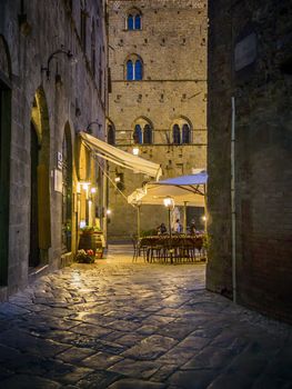 Night scene in Volterra with narrow alley and restaurant
