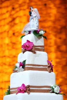 Elegance white wedding cake decorated with flower and groom and bride dolls on top