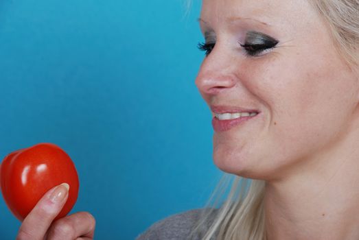 Blond womanl eating a tomato