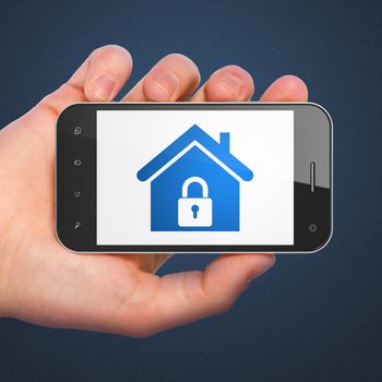 Safety concept: hand holding smartphone with Home on display. Generic mobile smart phone in hand on Dark Blue background.