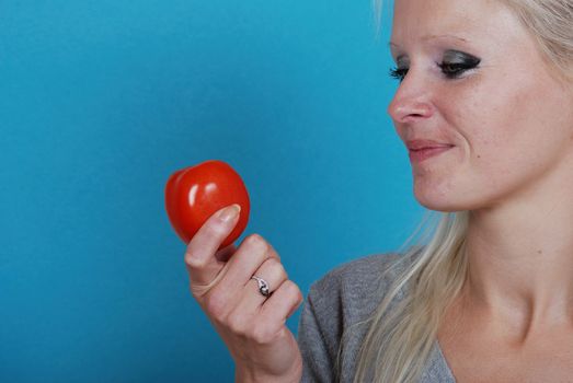 Blond womanl eating a tomato